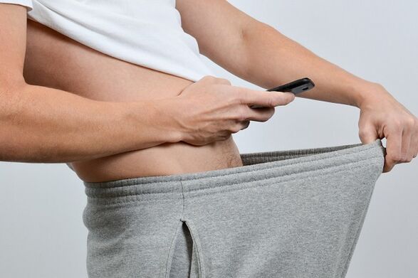 Seorang lelaki memandang ke bawah seluarnya di zakar yang diperbesar